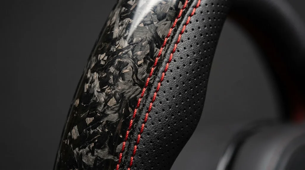 Close-up of forged carbon fiber, perforated Nappa leather and red stitching on a YINGGENE BMW steering wheel