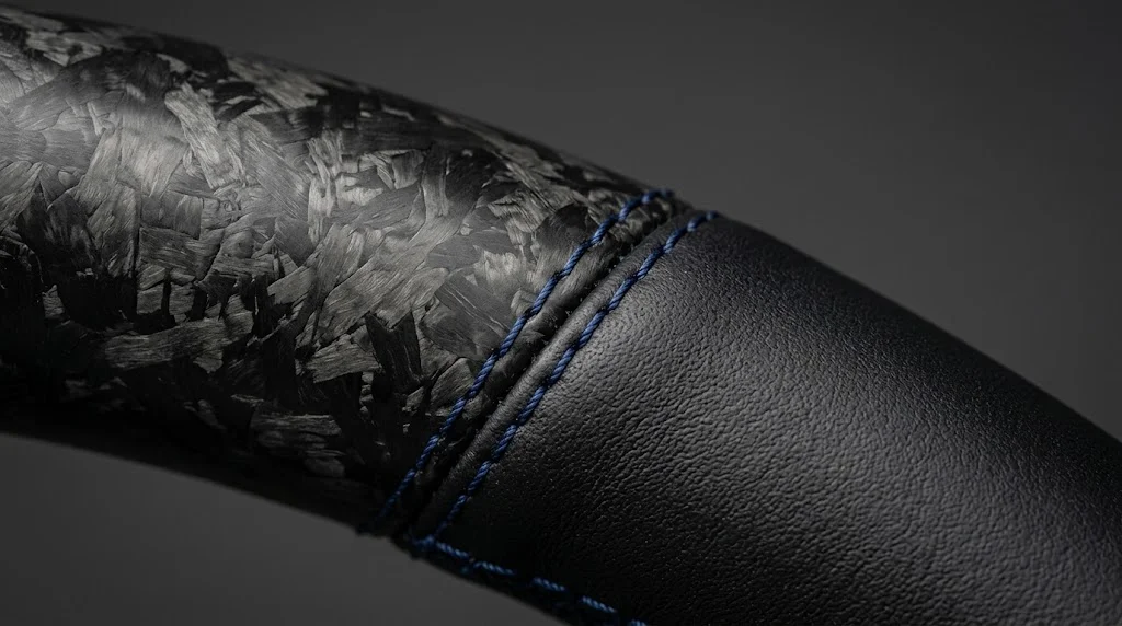 Close-up of matte forged carbon fiber, smooth black Nappa leather and deep blue stitching on a YINGGENE BMW 8 Series steering wheel